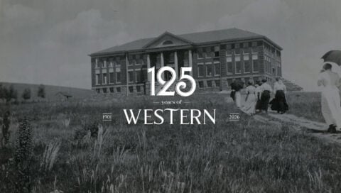 Members of the 1911 student body march up a dirt path through the weeds to Taylor Hall.