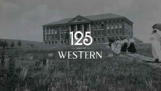 Members of the 1911 student body march up a dirt path through the weeds to Taylor Hall.