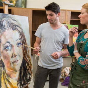 Tina Butterfield, assistant professor of art, discusses a painting with senior Silas McDonough in the painting studio of Quigley Hall.