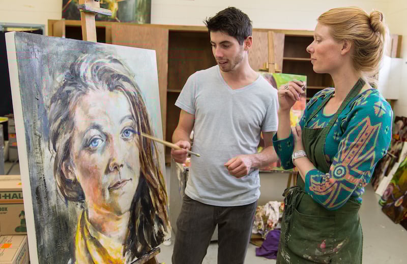 Tina Butterfield, assistant professor of art, discusses a painting with senior Silas McDonough in the painting studio of Quigley Hall.