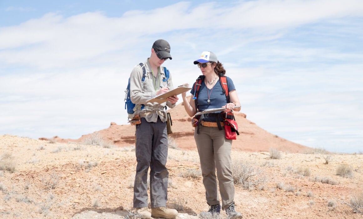Dr. Petrie assists Kurt with his field notes while standing in the desert.