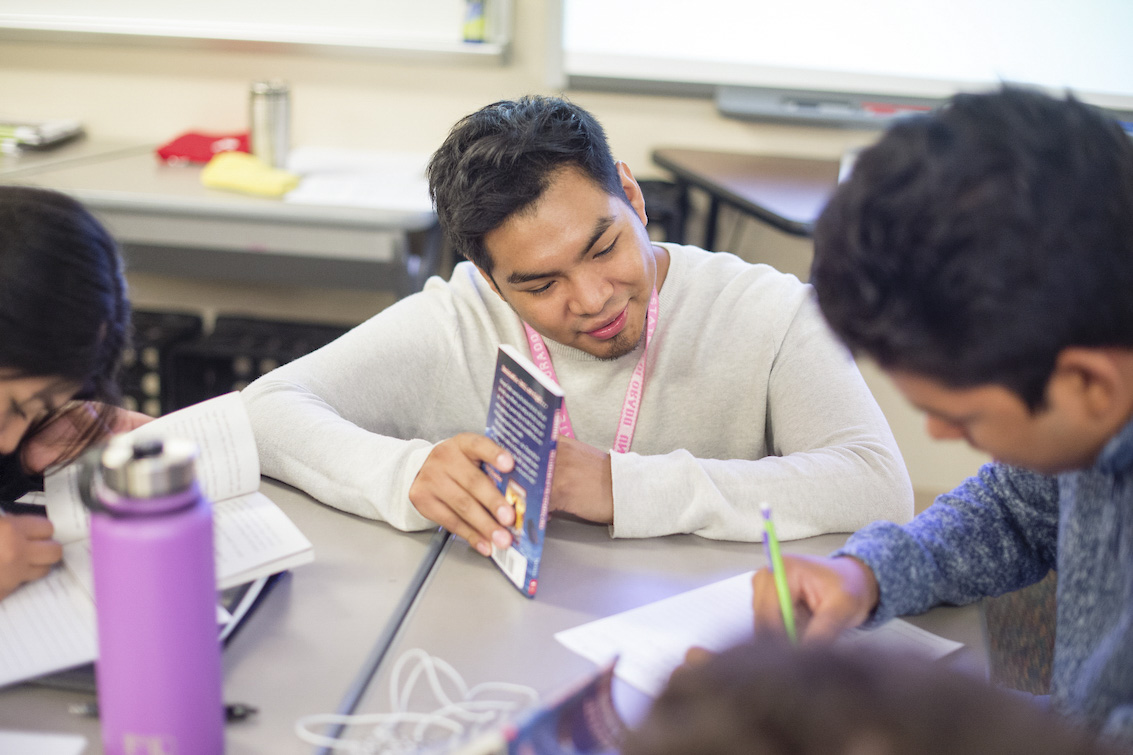 Student teacher, Cristian Aguilar, helping a student with classwork.