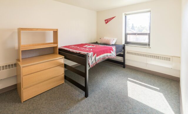 A raised bed and dresser inside a Chipeta Apartment bedroom.