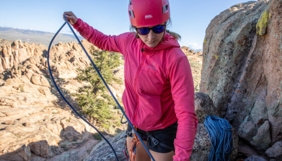 A woman unravels a length of rope while rock climbing.