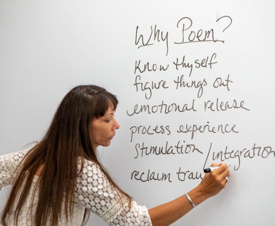 A professor writes on a whiteboard.