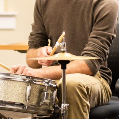 A student plays a drum kit