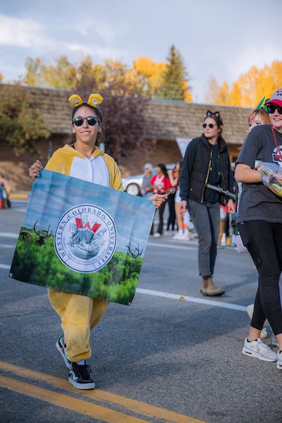 A member of the Wildlife Society wears a bear onesie and holds their banner during the Homecoming Parade.