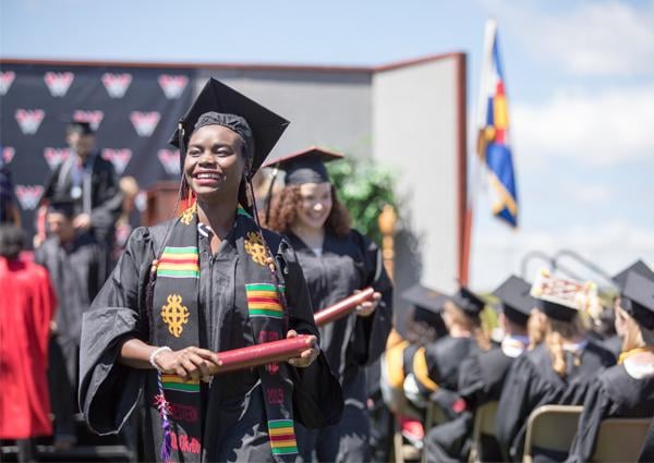 A student smiles while holding her diploma