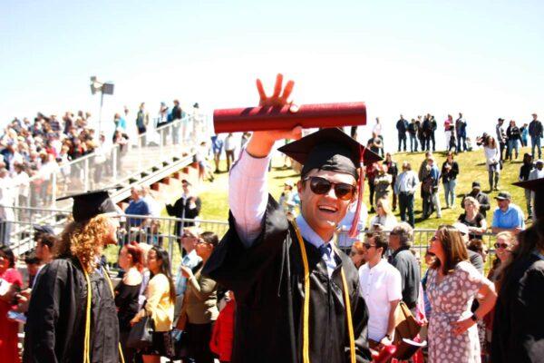 How to prepare for graduate school: Student holding diploma and waving