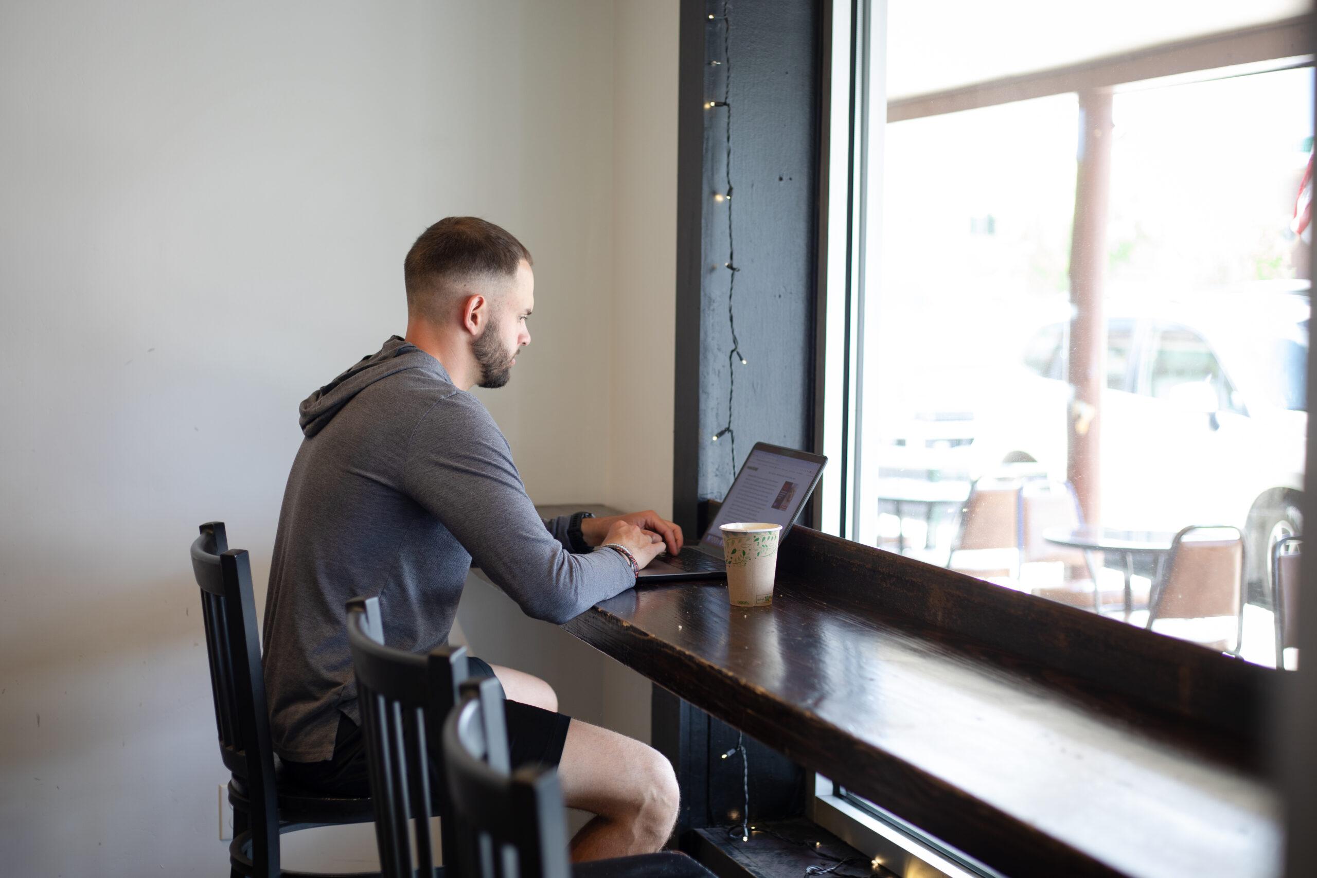 John Gonzales types on a laptop at Tributary Coffee for the ADC Photoshoot.