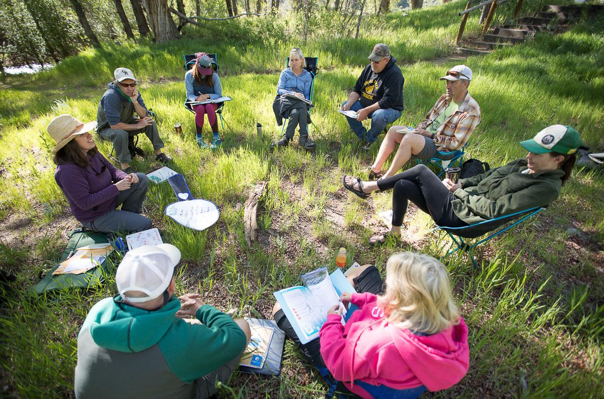 A group of adults learn in an outdoor classroom