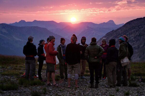 outdoor leadership degree programs: students standing in a circle at sunset by the mountains