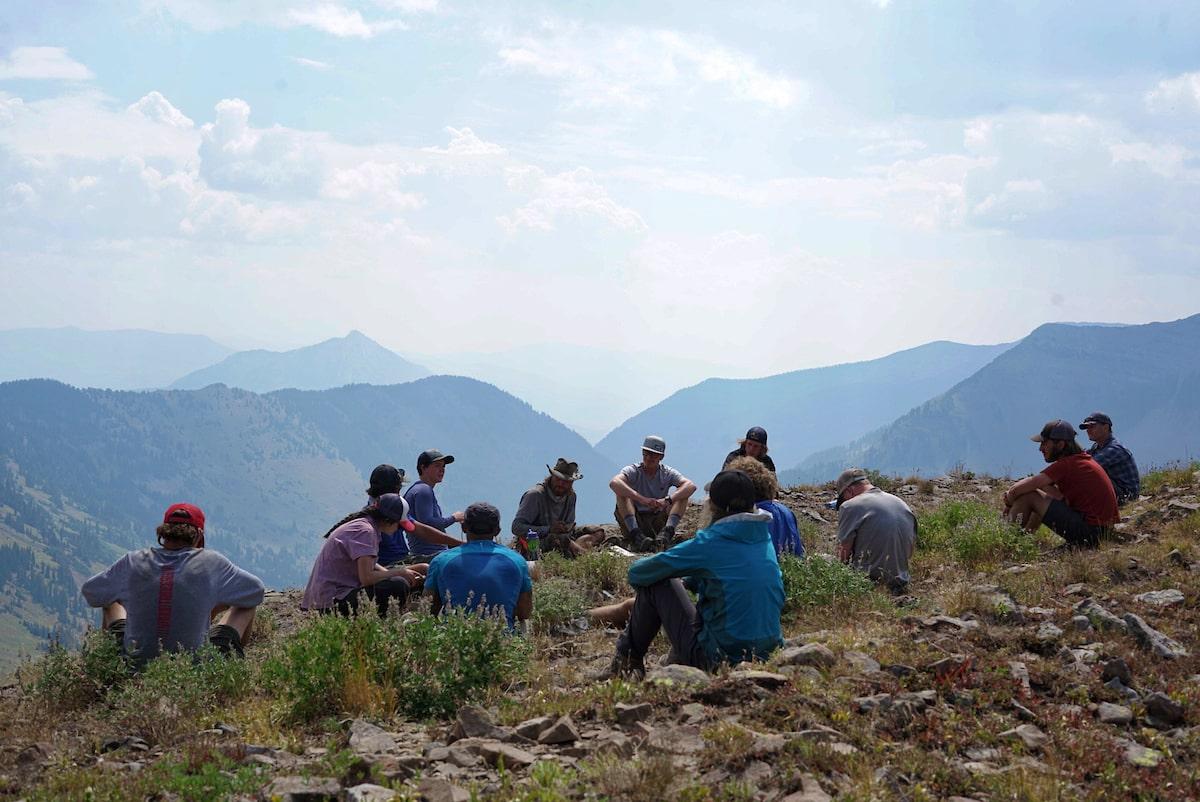 Students sitting in a group at the top of a mountain