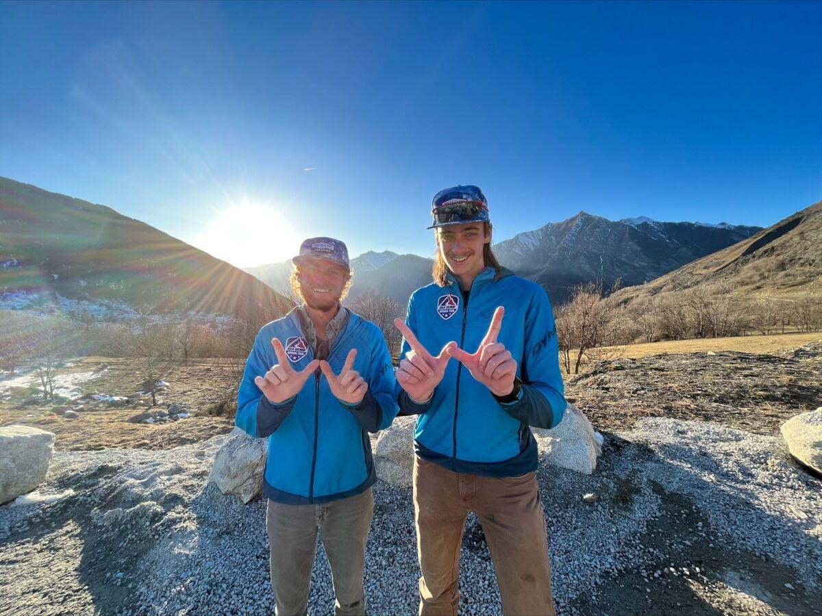 Breezley and Burke standing in front of mountains making the Western "W" 