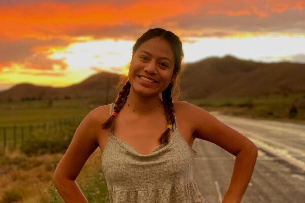 Johanna Hernandez poses for a photo with a sunset in the background.