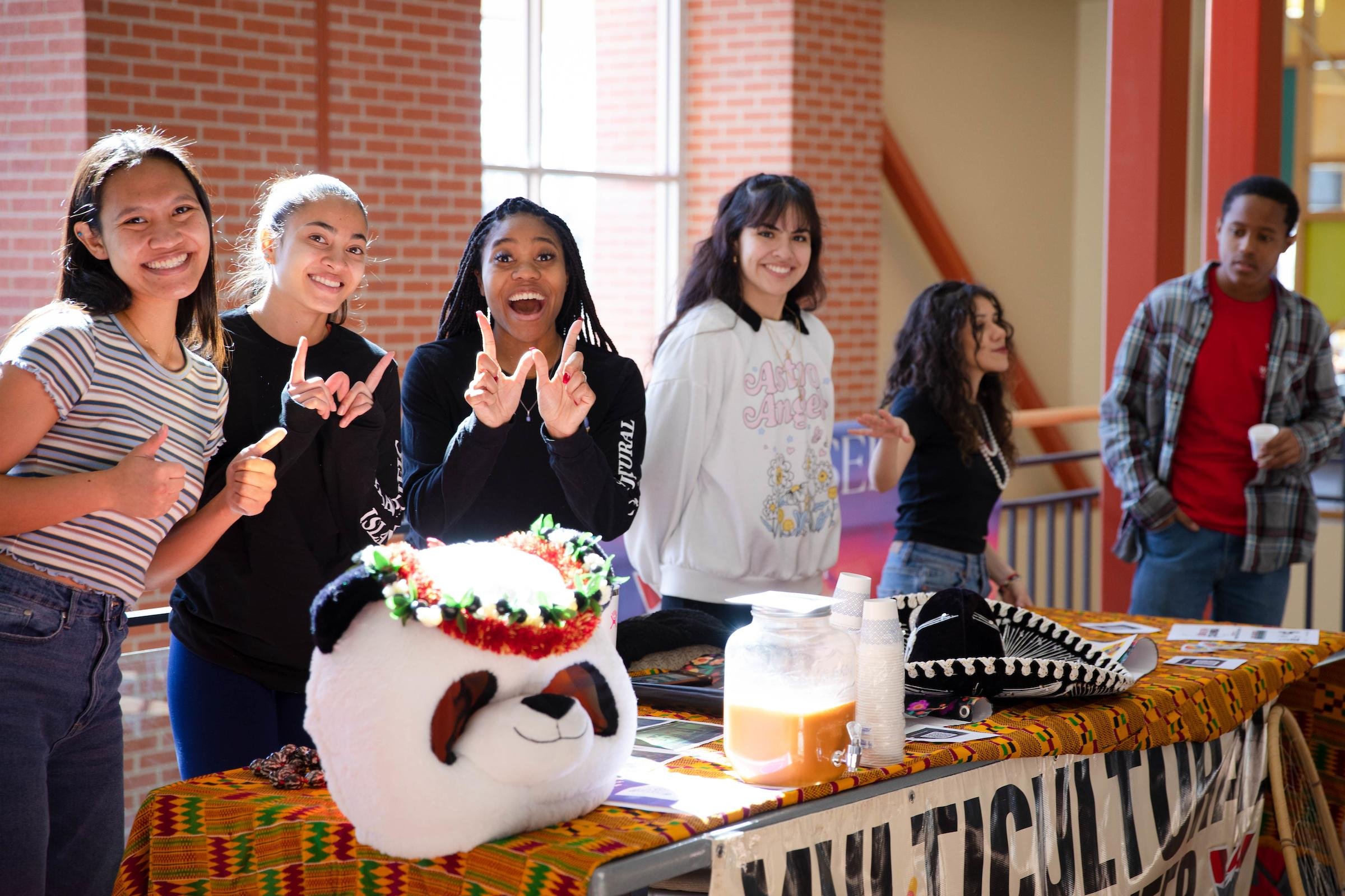 A few students pose for a photo behind the Multicultural Center table at the Admitted Student Day Club Fair.