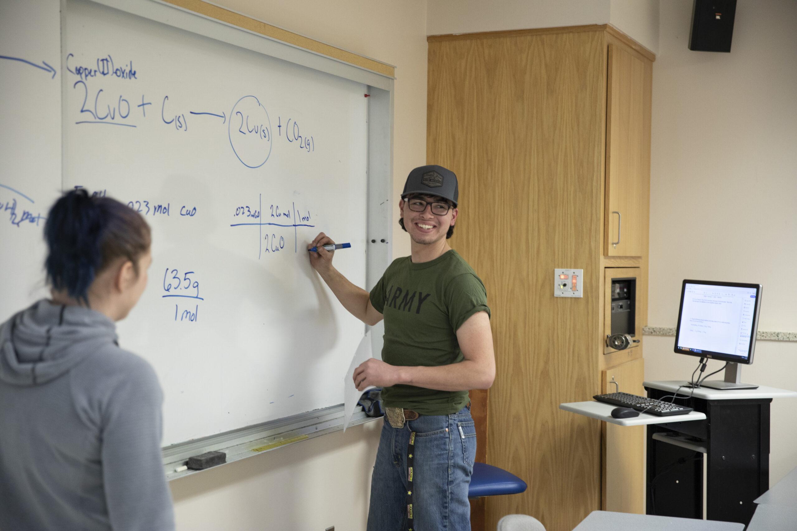 A CHEM 111 student works on a formula during an evening SI study session.