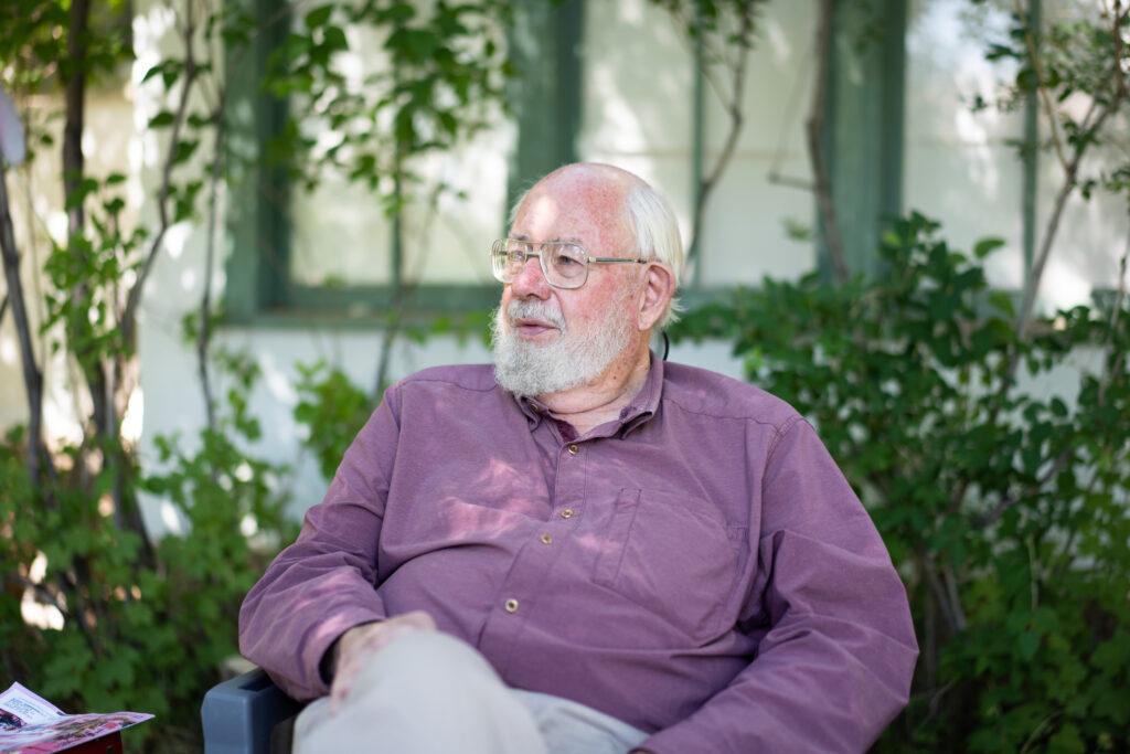 Butch Clark sits in a chair in his front yard and talks with a guest.