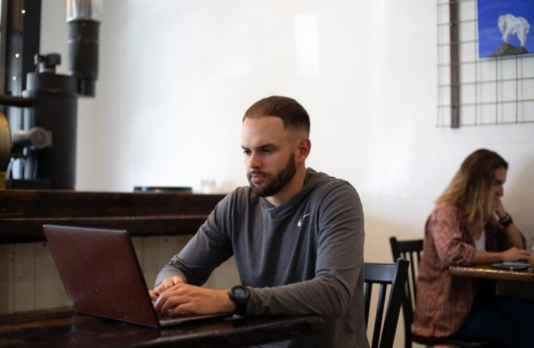 John Gonzales types on a laptop at Tributary Coffee for the ADC Photoshoot.