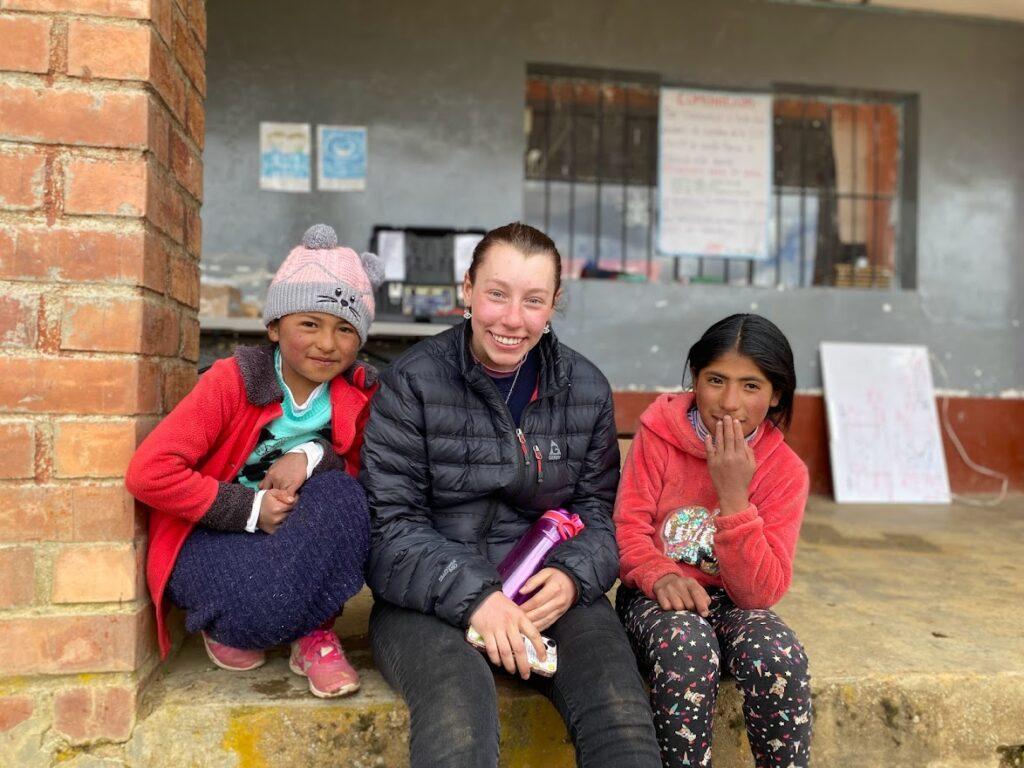 A Western student poses with two Peruvian children