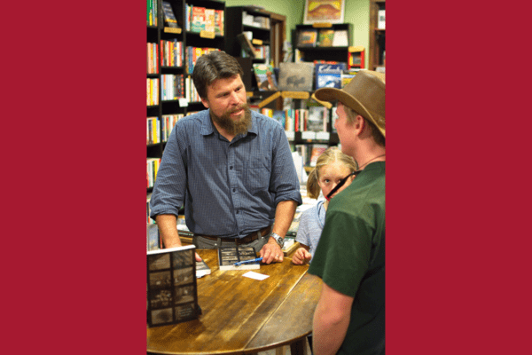 John Hausdoerffer speaks to a guest, who attended his book talk at Townie Books.