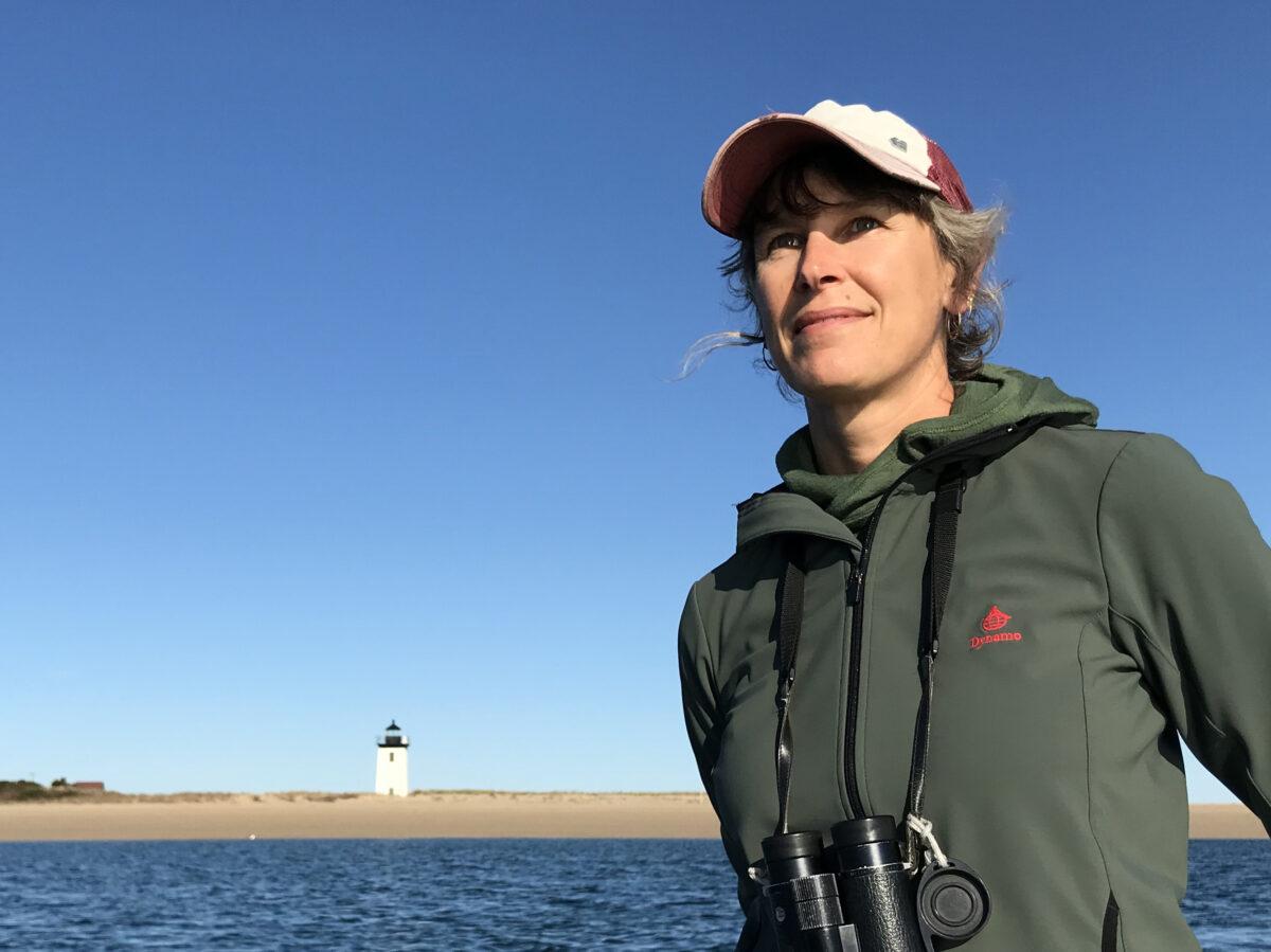 Elizabeth Bradfield poses in front of a lighthouse on a bay.
