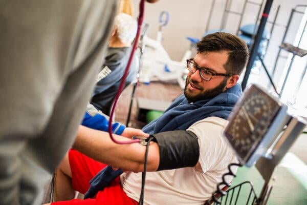 A student takes the blood pressure of a volunteer at a health event.