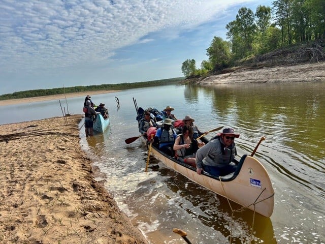 Western Graduate Students ride in a canoe down the Mississippi river.