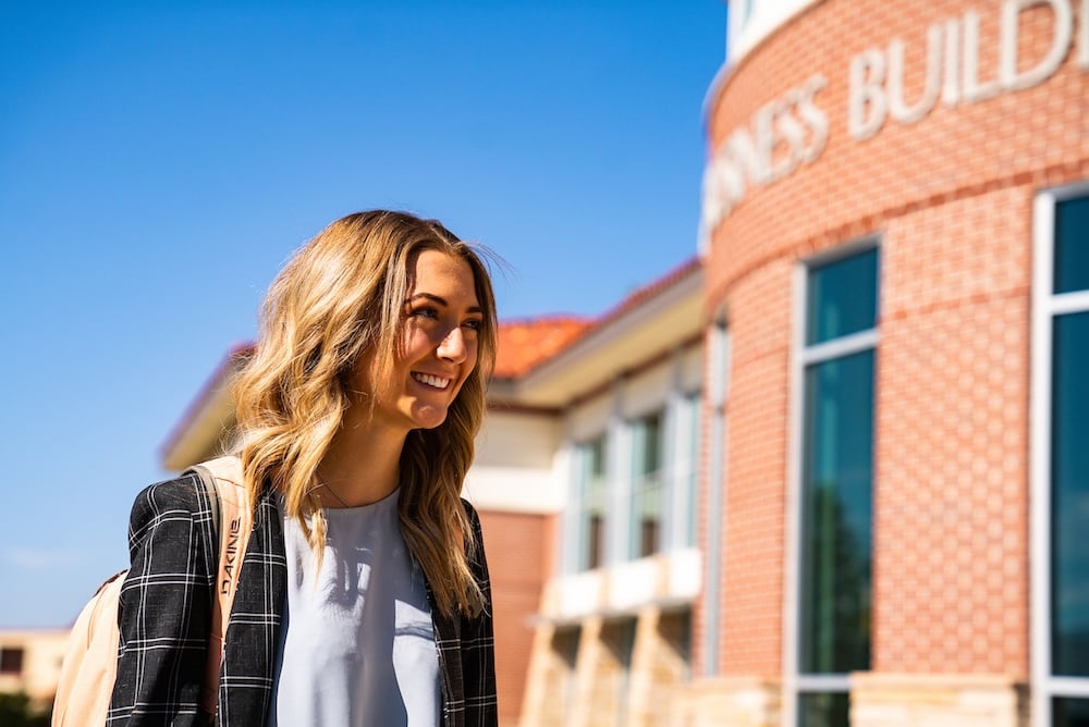 A student smiles as she walks past Borick Business Building.
