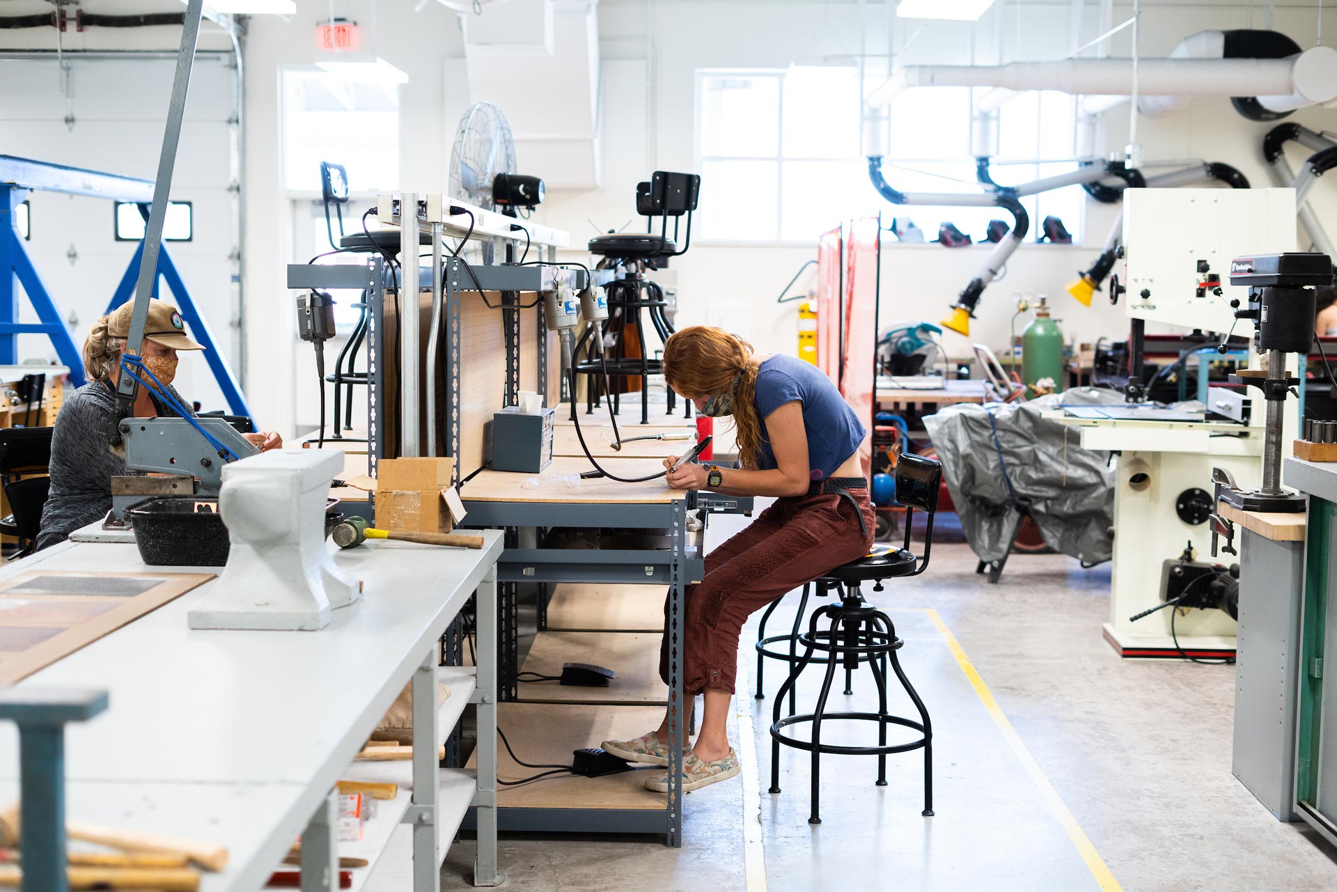 Two students work on making jewelry in an art class.