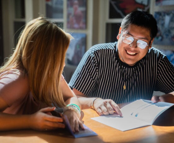 Two students read printed materials together.