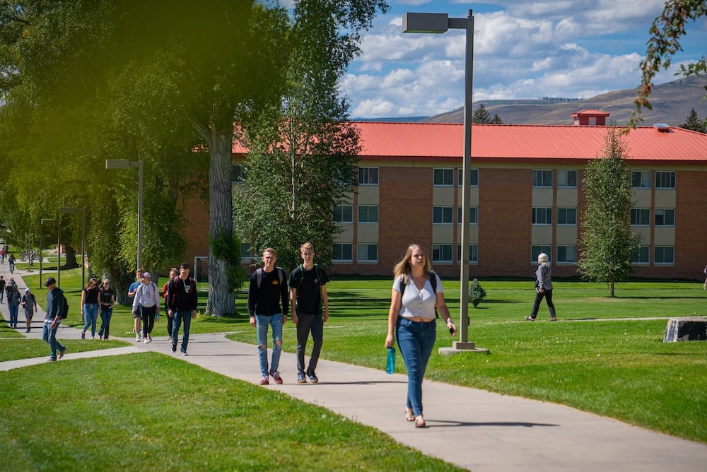 Several students walk across campus on their way to class.