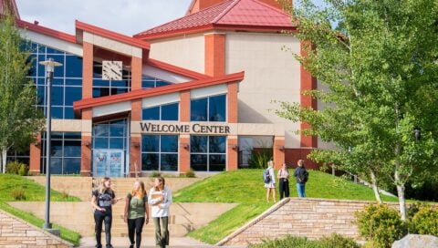 Several students walk together outside the Western Colorado University Welcome Center.
