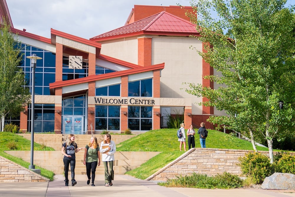 Several students walk together outside the Western Colorado University Welcome Center.