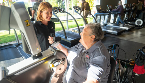 A professor assists a community member with a fitness exercise.