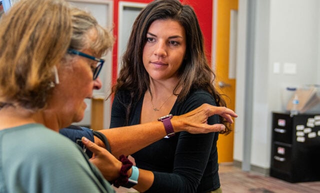 A student takes a community member's blood pressure.