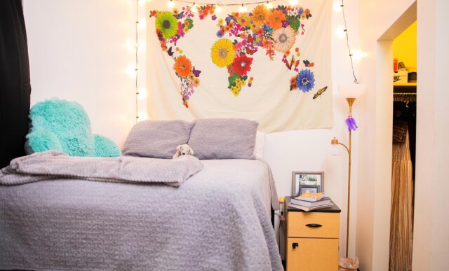 An apartment room with a bed, nightstand and colorful decorations.