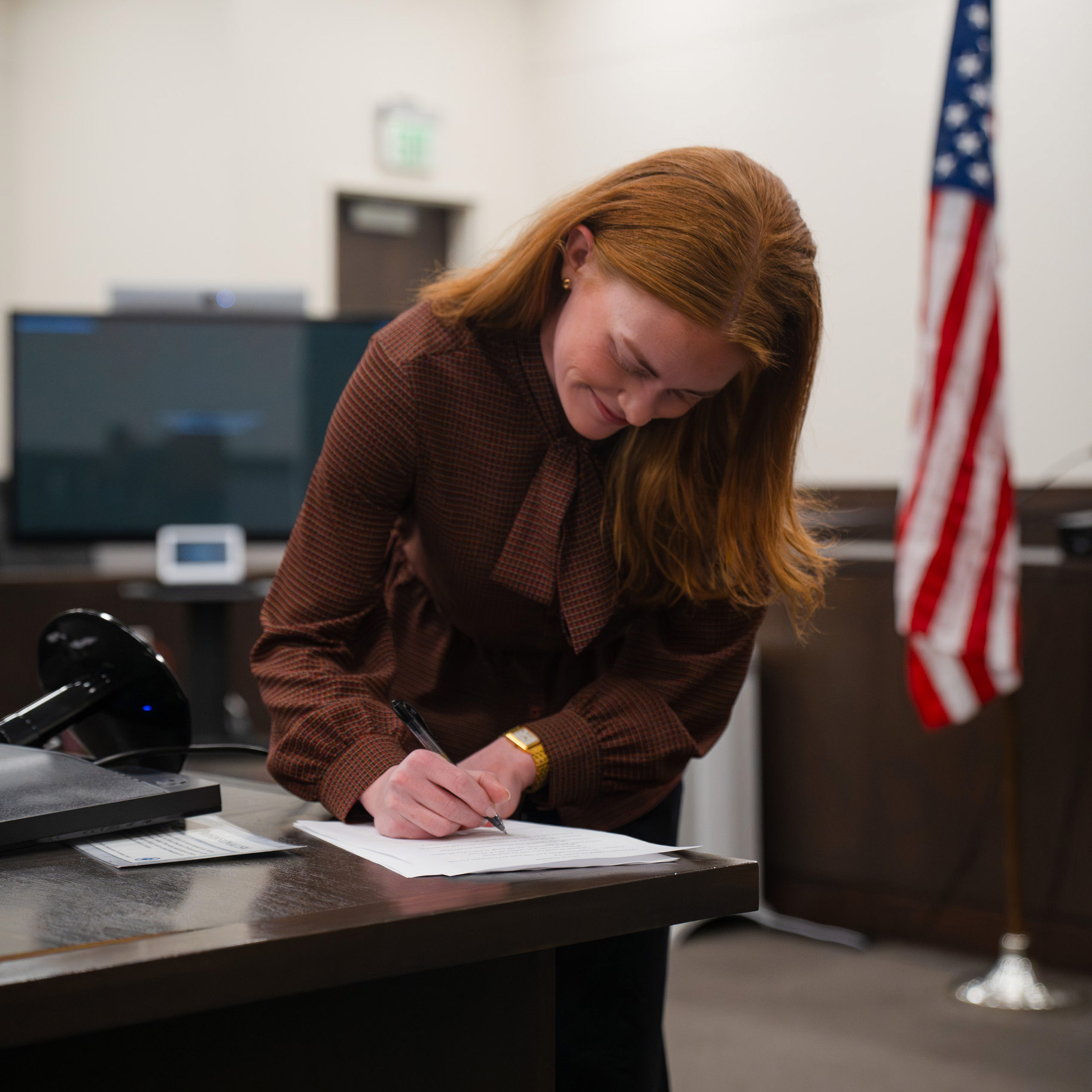 Tess Petersen signs a document.