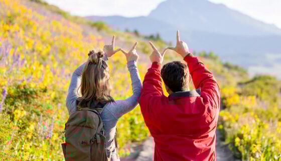 Two students hold the W above their heads in front of Teocalli Mountain at sunrise.