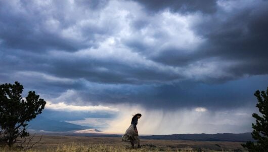 CMarie Fuhrman in a field of grass with a storm brewing behind her.