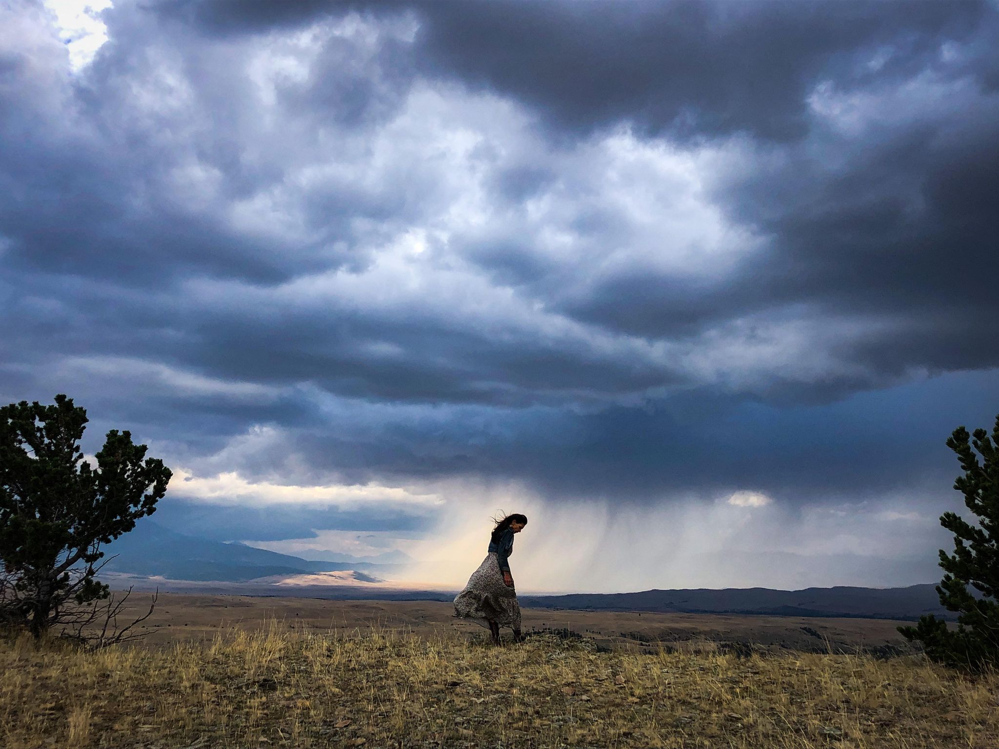 CMarie Fuhrman in a field of grass with a storm brewing behind her.