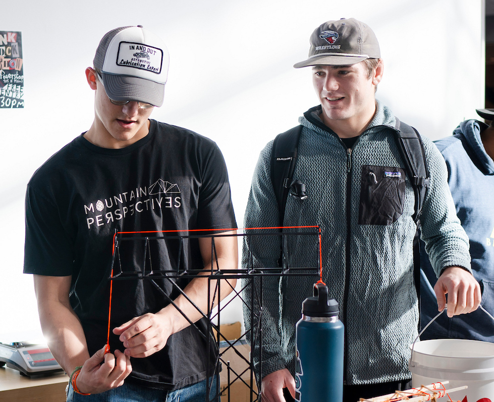 An engineering student prepares the model wooden crane he built for a break test at the end of semester celebration for the Engineering Partnership Program.