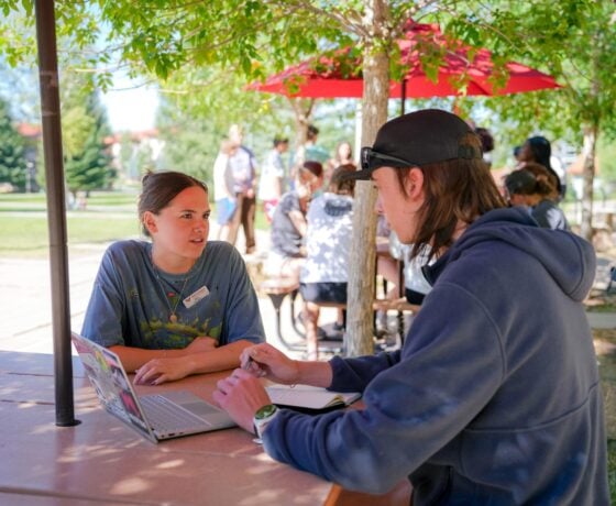 An EPIC Mentor gives advice to her student while seated at a picnic table outside.