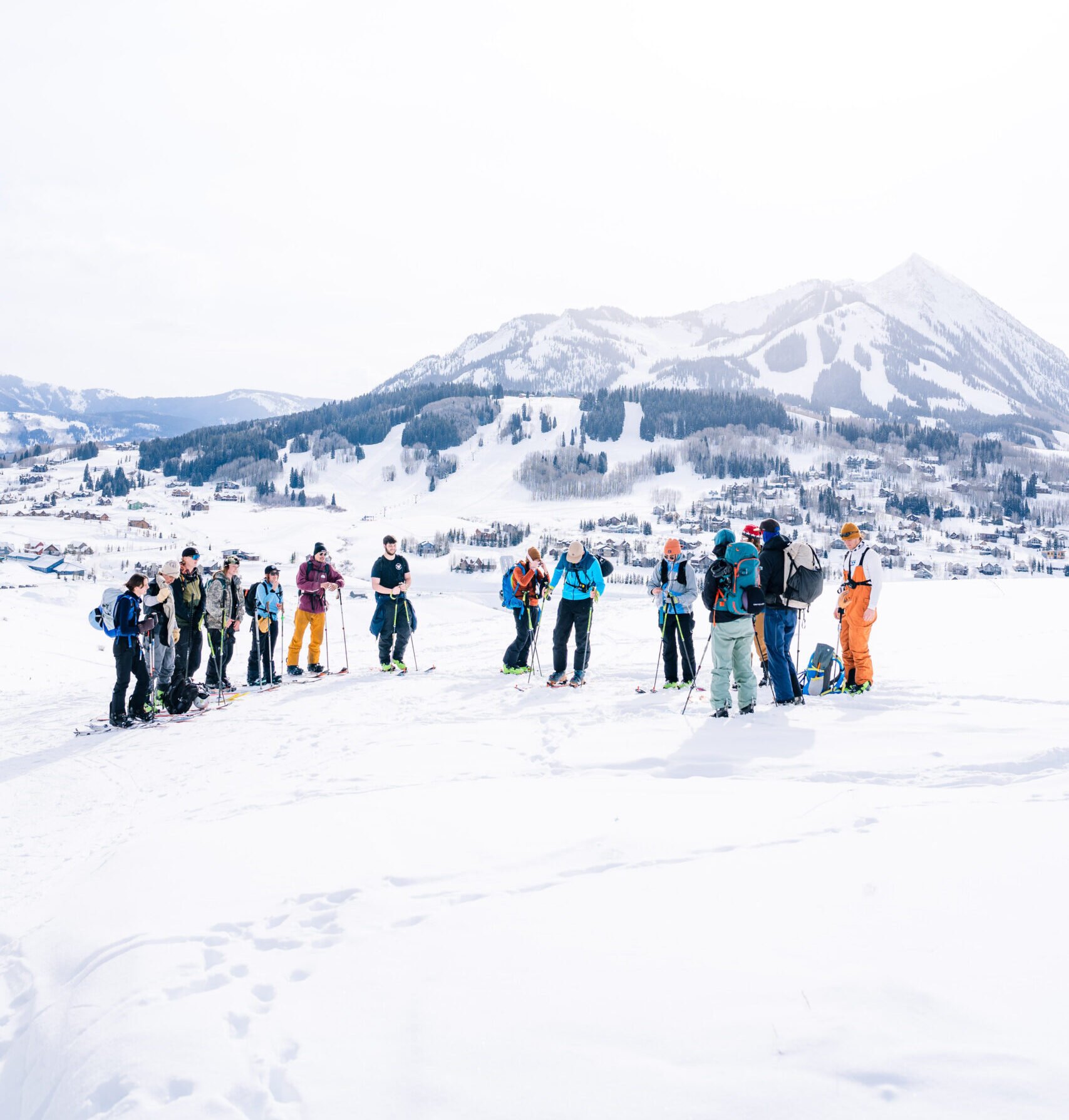 A small class of students gathers on their skin up Snodgrass Mountain. Mount Crested Butte can be seen in the background.