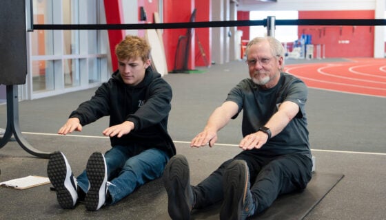 A student with the Wellness Elevated program coaches a community member through stretches and exercises at the Mountaineer Field House.