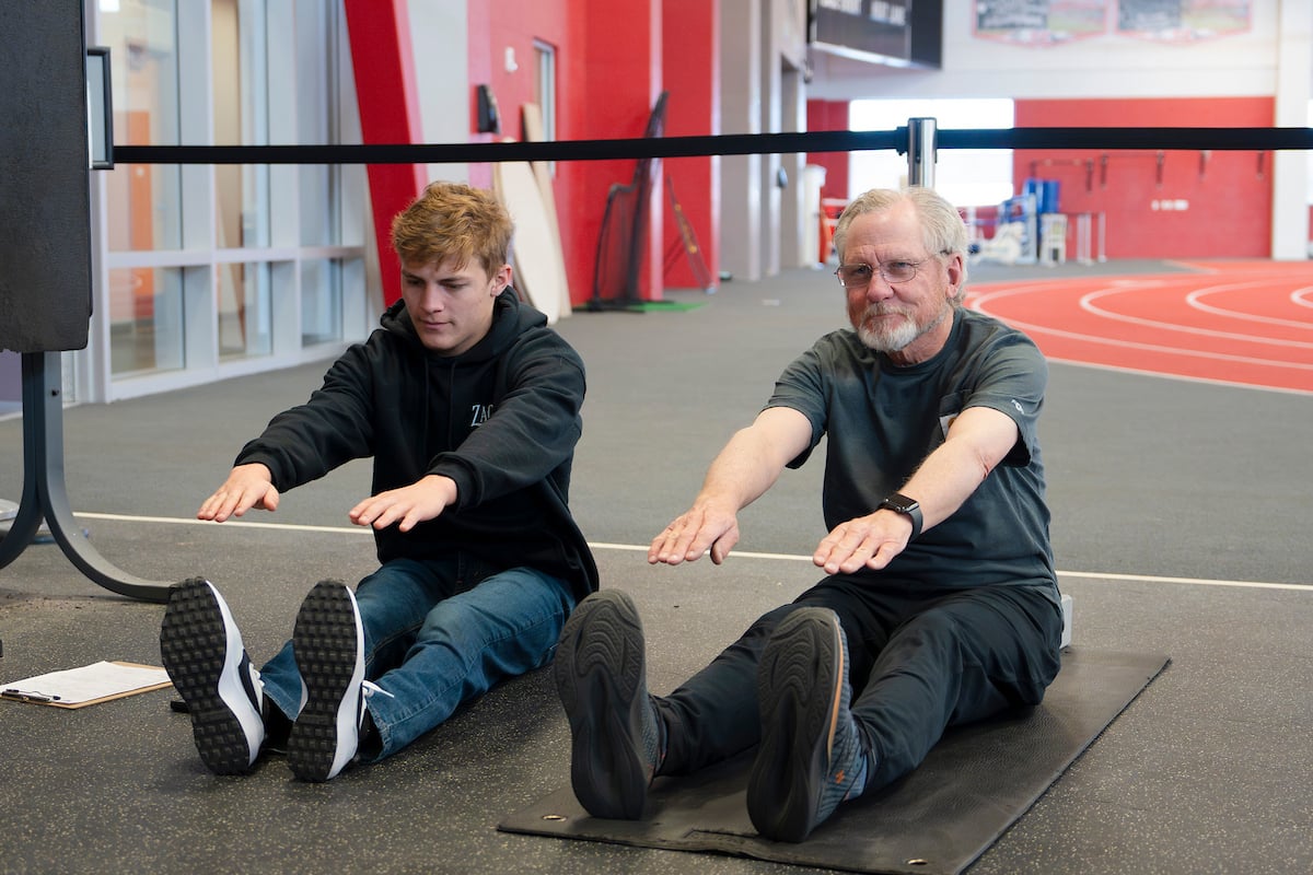 A student with the Wellness Elevated program coaches a community member through stretches and exercises at the Mountaineer Field House.