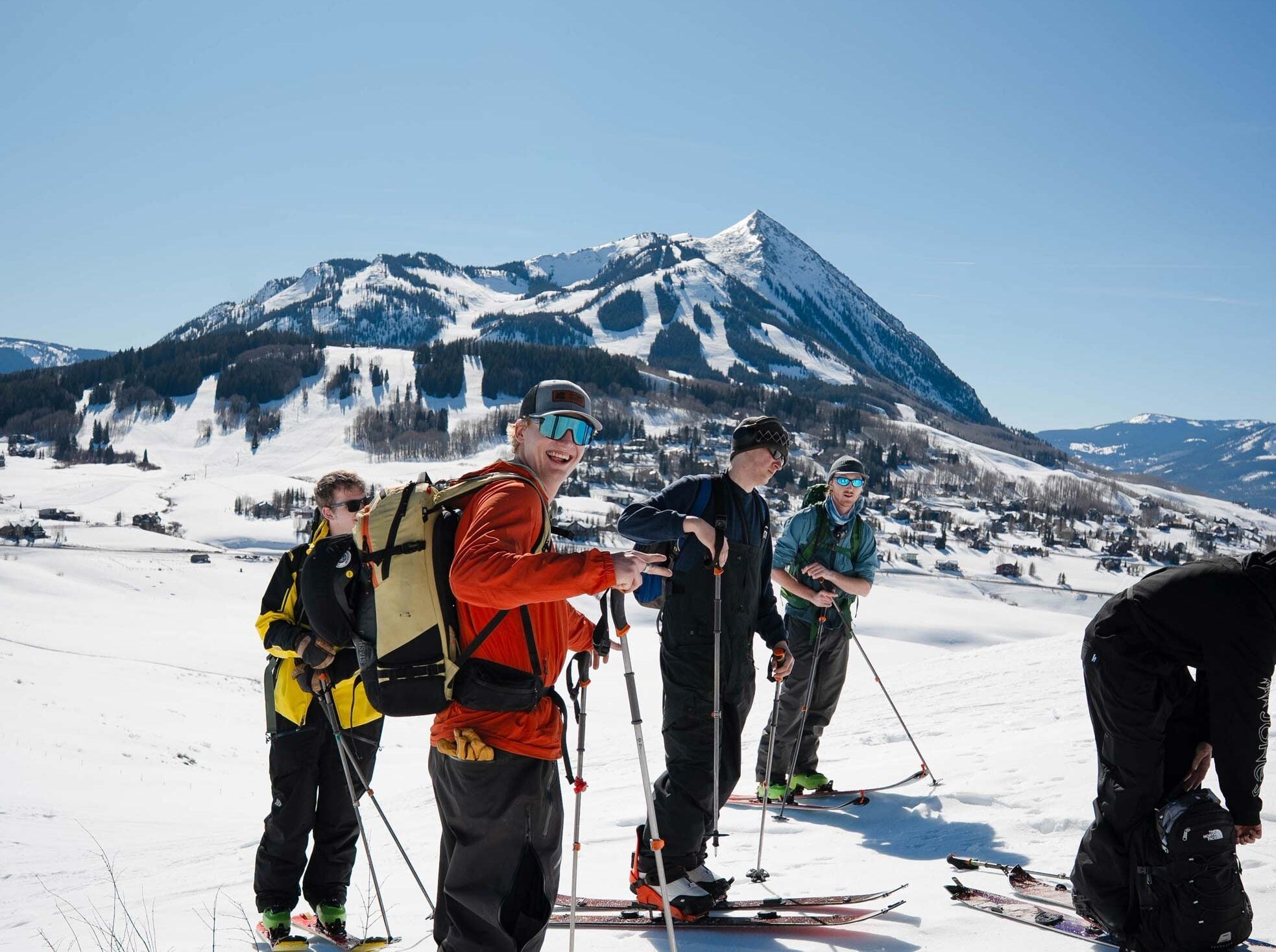 Students on a backcountry ski tour smile in front of a mountain.