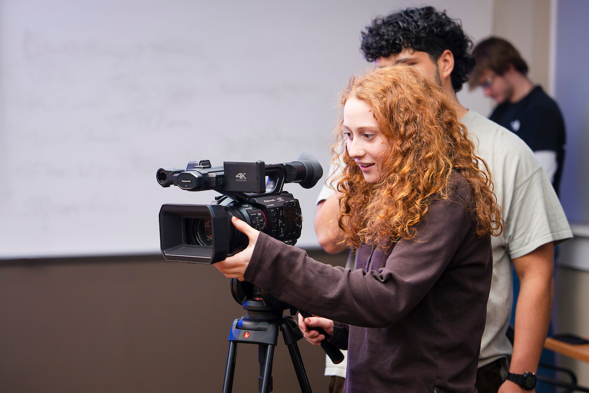A student practices framing different types of camera shots during an Intro to Film Studies course.