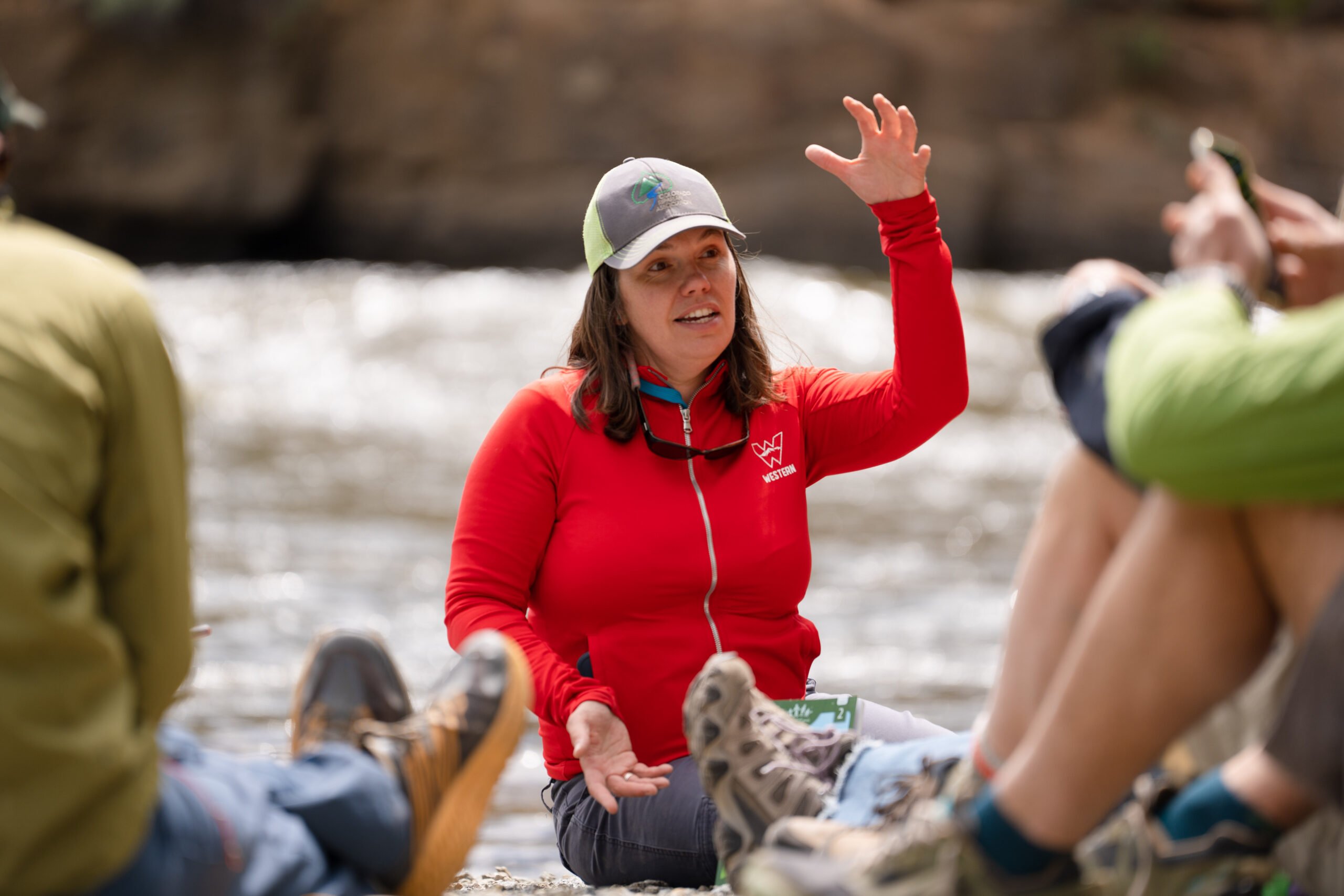 Sarah Johnson sits in a circle near the river with her class and lectures about riparian areas for her Rivers of the West class during the Teacher Institute.