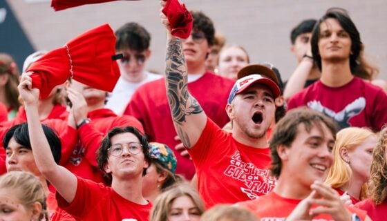 Two students cheer and wave tshirts in the air during a football game in Mountaineer Bowl.